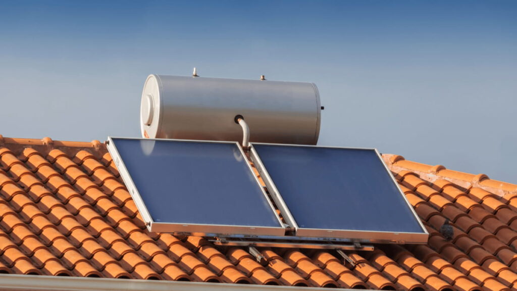 Een zonneboiler is geïnstalleerd op een klassiek rood pannendak.